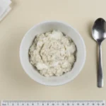 Kleine Portion feiner Haferflocken mit Skyr in einem kleinen weißen Schälchen