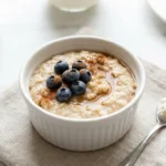 Kleiner Proteinporridge mit Beeren und Zimt in einer weißen Schüssel – bariatrisches Frühstück