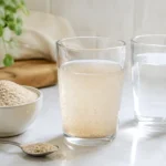 Frisch angerührtes Flohsamenschalen-Wasser neben Flohsamenschalen und einem zusätzlichen Glas Wasser