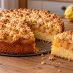Quittenkuchen mit Streuseln auf einer Springform, ein Stück zeigt den Quittenbelag